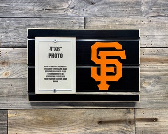 May include: A black and white wooden sign with an orange "SF" logo. The sign has a 4x6 inch photo frame with instructions on how to change the photo.