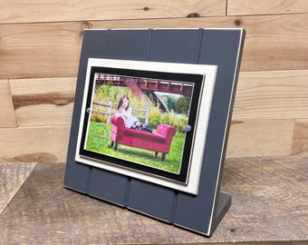 May include: A gray wooden picture frame with a white mat and a black and white photo of a girl sitting on a red chaise lounge. The frame has a rustic look and is perfect for displaying a favorite photo.