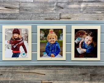 May include: A triple photo frame with three individual picture openings. The frame is light blue with a wooden plank design. Each opening contains a photograph of a child. The background is a weathered wood.