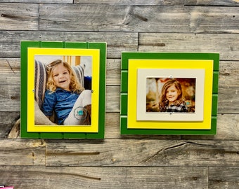 May include: Two framed photos of young girls, each with a green, yellow, and white frame. The frames are made of wood and have a rustic look. The photos are both of girls with long hair, smiling.