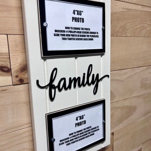May include: White wooden sign with black frames and instructions for changing a 4x6 inch photo. The sign says "family" in black cursive lettering.