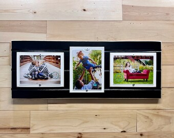May include: A black wooden picture frame with three white picture frames inside. The frames are arranged horizontally. The left frame shows two children hugging on a bridge. The middle frame shows a man holding a child in the air. The right frame shows a child sitting on a red couch.