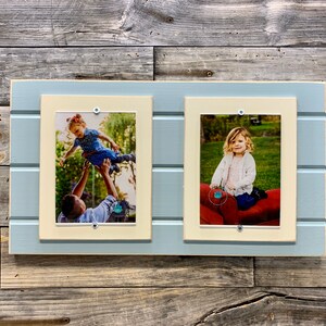 May include: A light blue wooden picture frame with two white mats and two photos of young children. The frame has a rustic look and is perfect for displaying family photos.