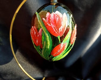 Een handbeschilderd glazen paasei met een rood tulpmotief op een glanzende groene achtergrond, een kerstversiering, een prachtig cadeau.
