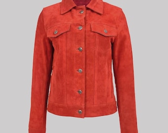 May include: A red-orange suede jacket with a classic collar and button-down front. The jacket features two chest pockets with button closures and long sleeves. The jacket is a solid colour and has a tailored fit.
