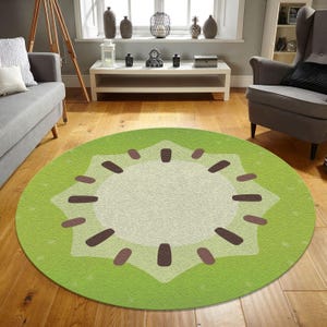 May include: A round green and brown rug with a kiwi fruit design. The rug has a light green background with a brown kiwi fruit in the center. The kiwi fruit has a star-shaped design with brown seeds.