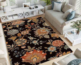 May include: A large, rectangular area rug with a black background and a detailed floral pattern in shades of orange, blue, and tan. The rug is placed in a living room setting, adding a decorative element to the space.