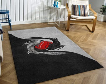 May include: A black and white area rug with a yin yang design featuring two fish, one black and one white, with a red circle in the centre. The rug has a grey background and is on a wooden floor.