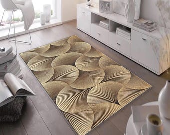 May include: A rectangular area rug with a repeating pattern of overlapping, concentric circles in shades of gold and brown. The rug is placed on a hardwood floor in a living room setting, adding a decorative element to the space.