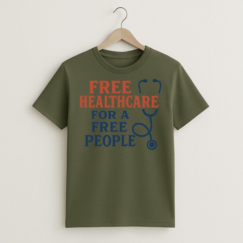 May include: Olive green t-shirt with the text "FREE HEALTHCARE FOR A FREE PEOPLE" in red and blue. A blue stethoscope graphic is on the right side of the text. The t-shirt is hanging on a wooden hanger.