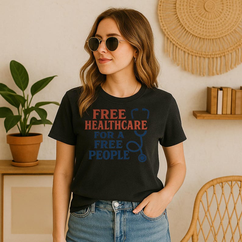 May include: Black t-shirt with the text "FREE HEALTHCARE FOR A FREE PEOPLE" in red and blue. The design includes a stethoscope graphic. The shirt is worn by a person wearing sunglasses and blue jeans.