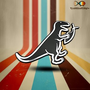 May include: Black and white enamel pin featuring a dinosaur holding a cross. The dinosaur is in a running pose with its mouth open. The pin is on a striped background.