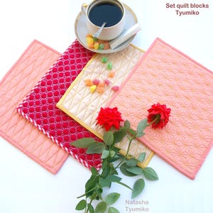 Könnte beinhalten: Set aus drei gesteppten Stoffquadraten in Rosa, Rot und Gelb mit einem Rautenmuster. Die Quadrate sind auf einer weißen Oberfläche mit einer Tasse Kaffee und ein paar bunten Bonbons angeordnet.