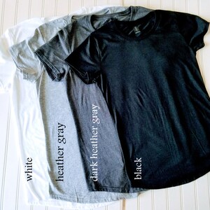 K&ouml;nnte beinhalten: Vier T-Shirts in verschiedenen Farben: Wei&szlig;, Heather Grey, Dunkel Heather Grey und Schwarz. Die Shirts sind gefaltet und &uuml;bereinander gestapelt. Die Farben der Shirts sind unter jedem Shirt beschriftet.