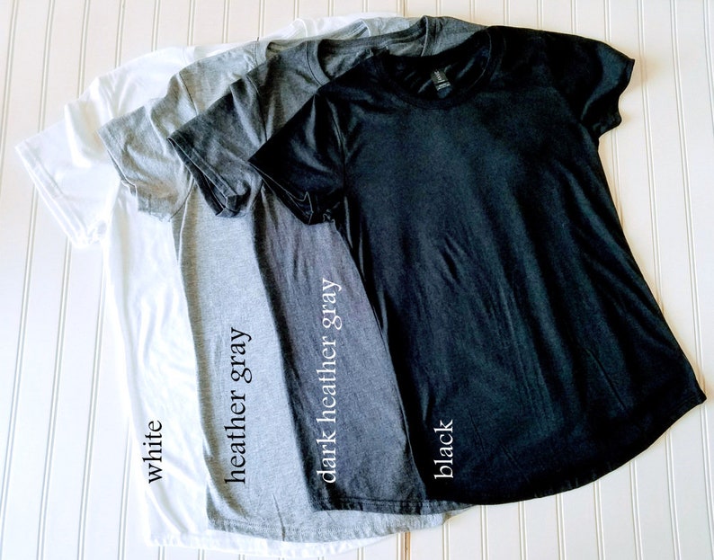 K&ouml;nnte beinhalten: Vier T-Shirts in verschiedenen Farben: Wei&szlig;, Heather Grey, Dunkel Heather Grey und Schwarz. Die Shirts sind gefaltet und &uuml;bereinander gestapelt. Die Farben der Shirts sind unter jedem Shirt beschriftet.