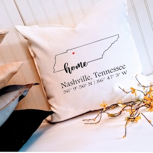 May include: White throw pillow with a black outline of the state of Tennessee and the text "home" in cursive. The text "Nashville, Tennessee 36° 9' 56" N / 86° 47' 3" W" is also printed on the pillow.