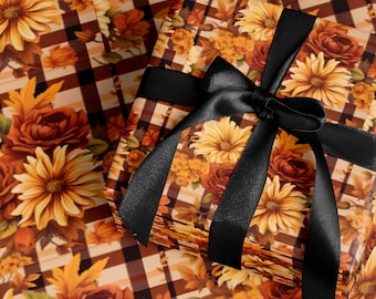 Op de afbeelding: Een cadeau verpakt met een zwarte satijnen strik. Het cadeaupapier heeft een bloemenpatroon met zonnebloemen, rozen en herfstbladeren in oranje, geel en bruin. De achtergrond heeft een ruitpatroon.