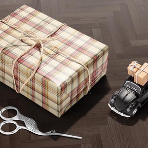 A gift box with a bow, a pair of scissors, and a small toy car on a wooden floor.