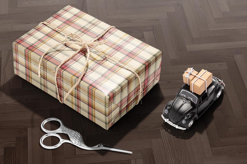 A gift box with a bow, a pair of scissors, and a small toy car on a wooden floor.