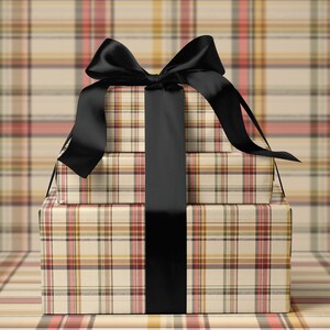 A stack of three gift boxes with a black ribbon tied around the middle box, set against a plaid background.
