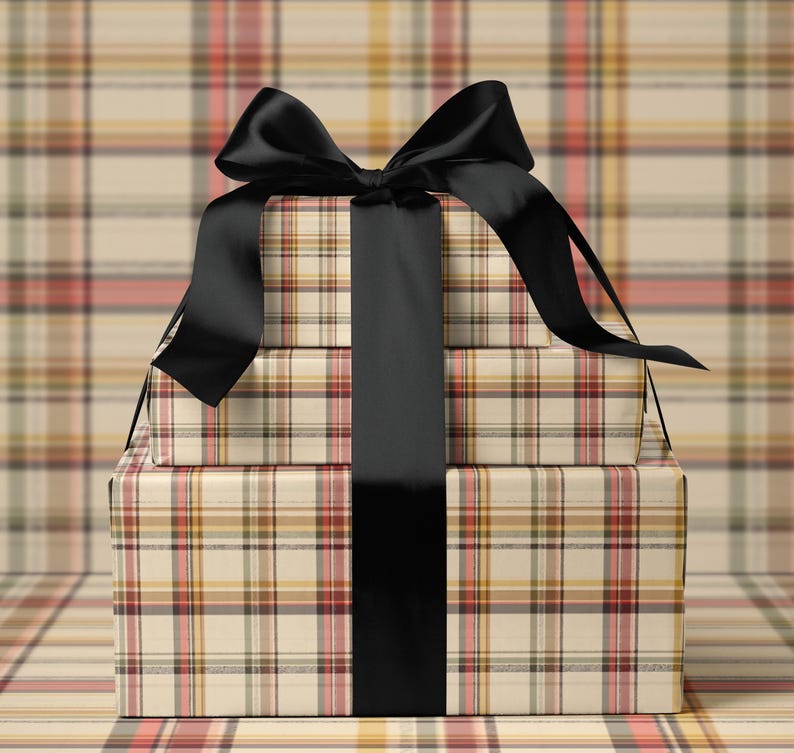 A stack of three gift boxes with a black ribbon tied around the middle box, set against a plaid background.
