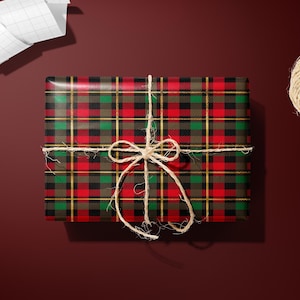 a gift wrapped in a red and black plaid wrapping paper, tied with a string bow, and accompanied by a spool of twine, a pair of scissors, and a piece of paper.