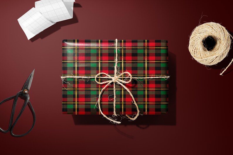 a gift wrapped in a red and black plaid wrapping paper, tied with a string bow, and accompanied by a spool of twine, a pair of scissors, and a piece of paper.