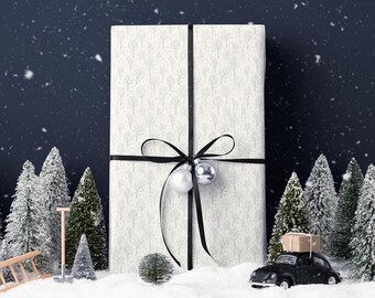 May include: A large, rectangular gift wrapped in white paper with a subtle tree pattern, tied with a black ribbon and bow. Silver ornaments hang from the bow. Miniature evergreen trees and a black toy car with a package on top sit in the snow.