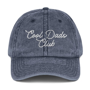 May include: A vintage-style, blue denim baseball cap with white embroidered text that reads "Cool Dads Club".