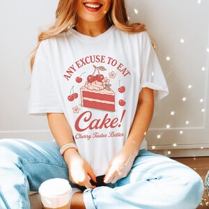a woman sitting on the floor with a cake on her shirt
