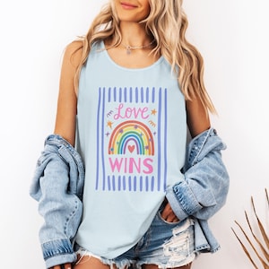 Puede incluir: Una taza de cerámica blanca con un asa negra y el texto "But First, Coffee" en negrita negra. La taza está sobre una superficie de madera. La taza mide aproximadamente 10 cm de alto.