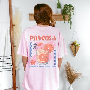a woman in a pink shirt standing in front of a wall