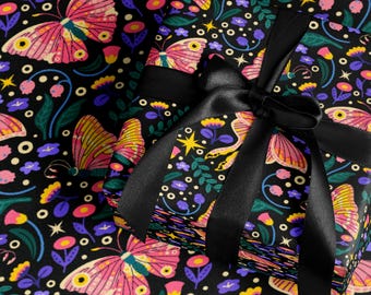 Puede incluir: Papel de regalo negro con un colorido diseño de mariposas y flores. El regalo está atado con una cinta de satén negra. Las mariposas son rosas, amarillas y naranjas, sobre un fondo negro.