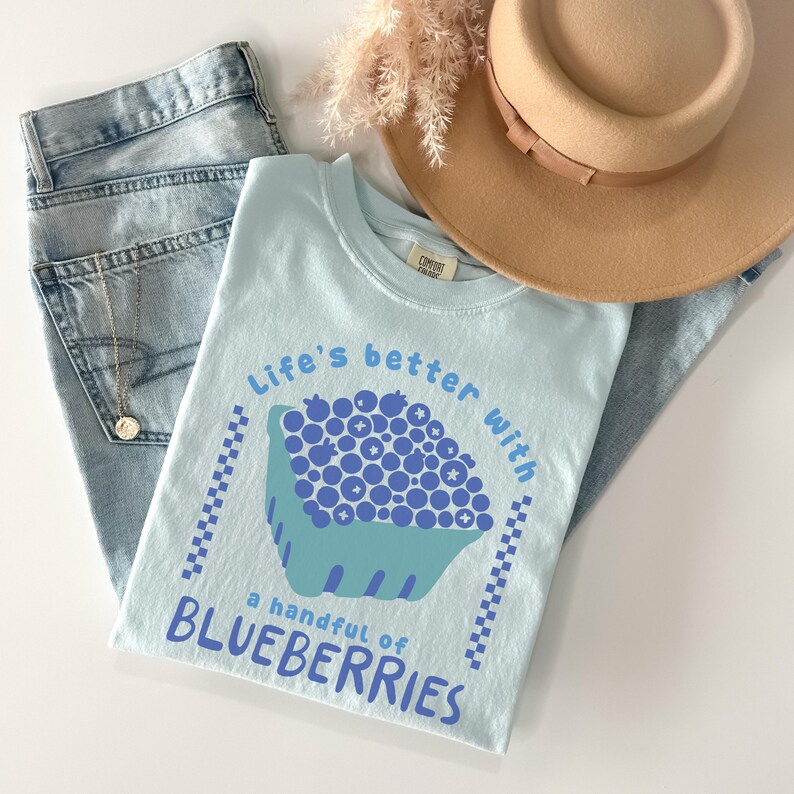 a hat, jeans, and a t - shirt on a white surface