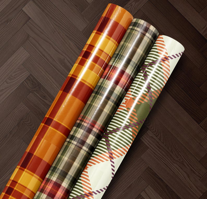 Three rolls of colorful, patterned wrapping paper are arranged on a wooden floor.