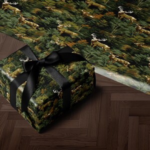 A gift box wrapped in a camouflage pattern with a black ribbon, placed on a wooden floor.