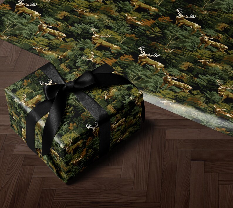 A gift box wrapped in a camouflage pattern with a black ribbon, placed on a wooden floor.