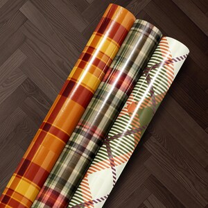 Three rolls of colorful, patterned wrapping paper are arranged on a wooden floor.