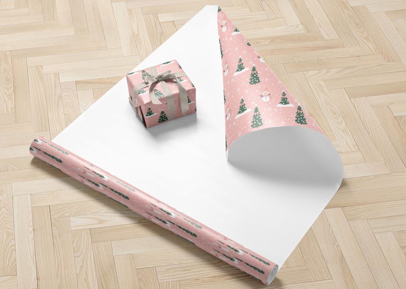 A pink and white Christmas-themed gift wrapping paper with a snowman and pine trees on it, along with a small gift box wrapped in the same paper.