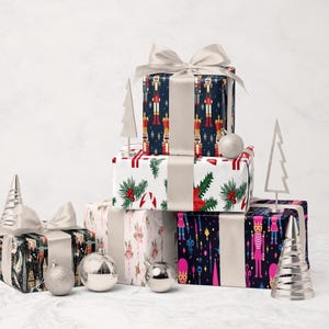 A stack of colorful gift boxes with bows, ornaments, and Christmas trees on a white marble surface.