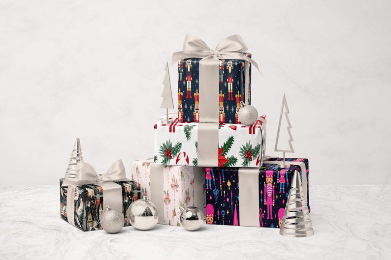 A stack of colorful gift boxes with bows, ornaments, and Christmas trees on a white marble surface.