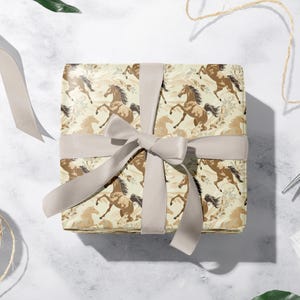 a gift box with a horse patterned wrapping paper, a ribbon, and some crafting supplies such as scissors and twine.