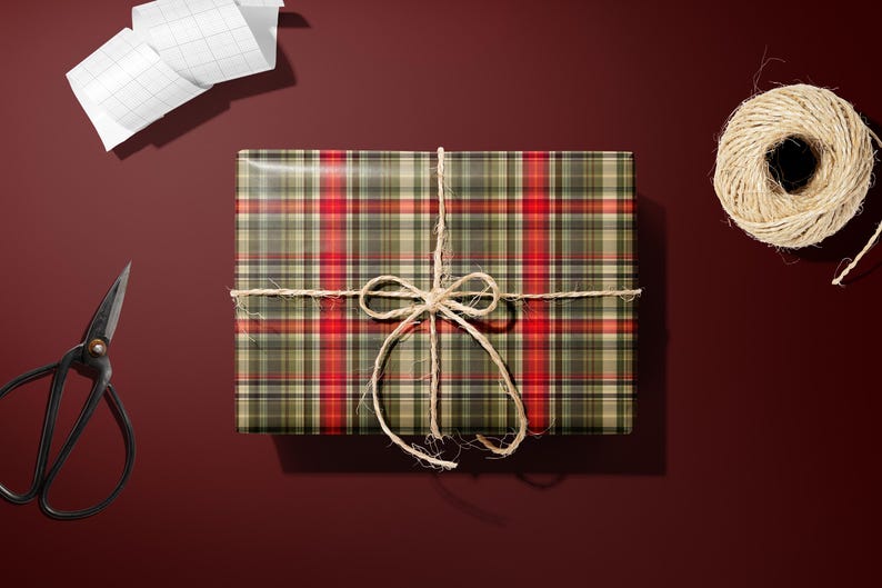 a gift box wrapped in a plaid pattern, tied with a twine bow, and accompanied by a pair of scissors and a spool of twine on a dark red background.