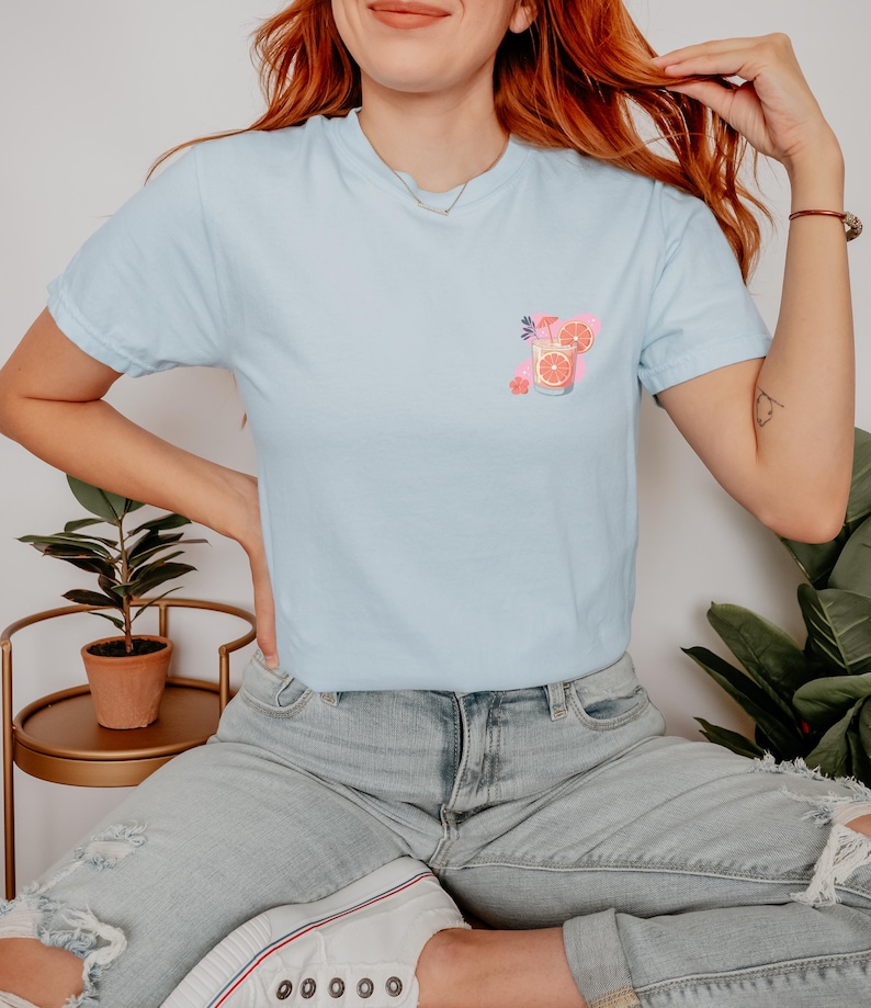 a woman with red hair wearing a blue shirt and ripped jeans