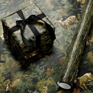 a gift box with a black ribbon, placed on top of a roll of wrapping paper with a deer pattern.
