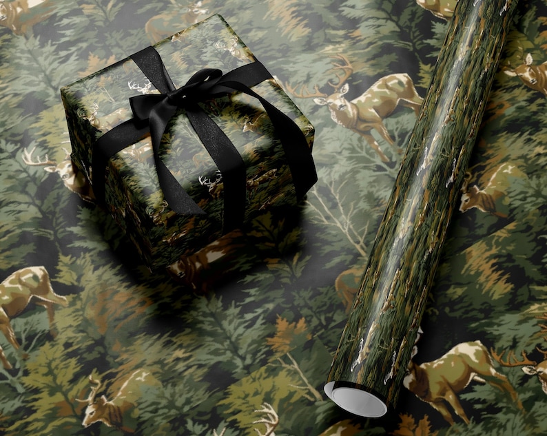 a gift box with a black ribbon, placed on top of a roll of wrapping paper with a deer pattern.