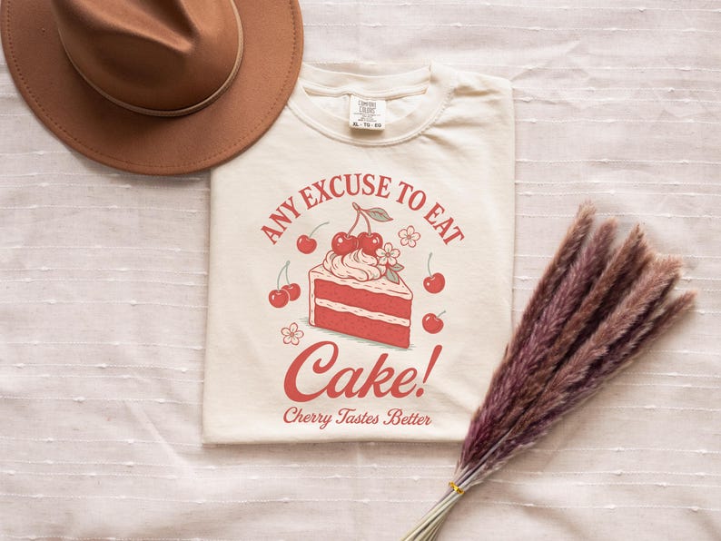 a t - shirt with a cake on it next to a straw hat