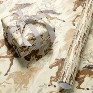 a gift box with a ribbon and a roll of wrapping paper with a horse pattern on it, both placed on a beige and brown patterned background.