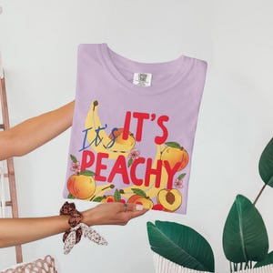 Trendy Its Peachy Shirt, Cute Fruit Graphic Tee, Fun Summer T-Shirt, Casual Graphic Top, Perfect Gift for Her, Colorful Peach Design