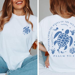 a woman sitting on a bed wearing a t - shirt with a turtle on it